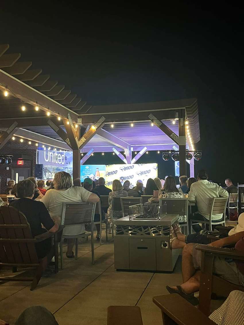 Evening crowd under string lights at B100 Songwriters in the Round